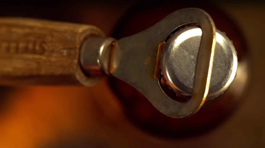 Macro shot: Wooden-handled bottle opener prying a silver bottle cap.