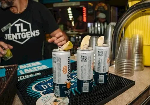 Three Corona beers with lime wedges on a bar mat.