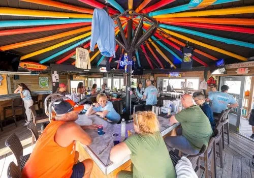 Lively bar with a colorful radial ceiling pattern and patrons.