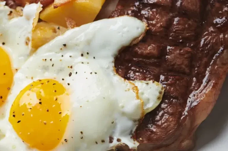 Grilled steak, two runny fried eggs, and roasted potatoes.