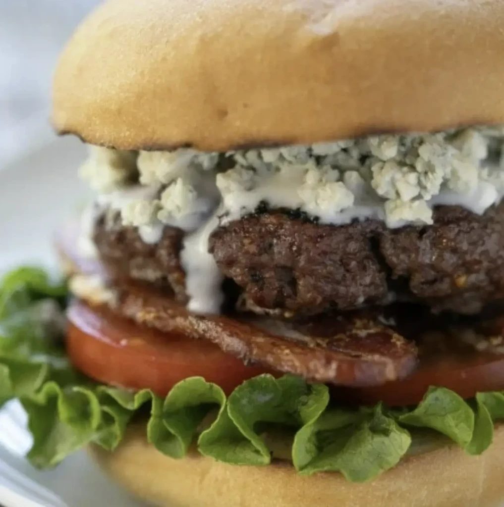 Gourmet beef burger with blue cheese, bacon, tomato, and lettuce.