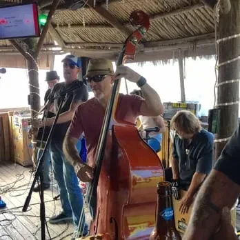 Man plays upright bass in a live band at rustic bar.