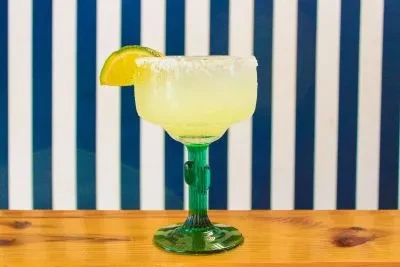 Margarita in a cactus-stem glass, with salted rim and lime.