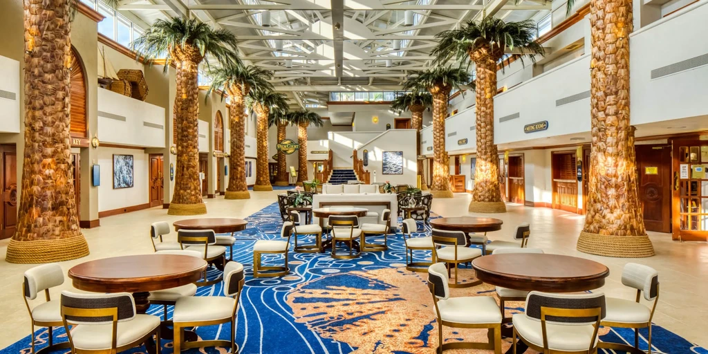 Resort-style atrium with palm-tree columns, skylights, and blue carpet.