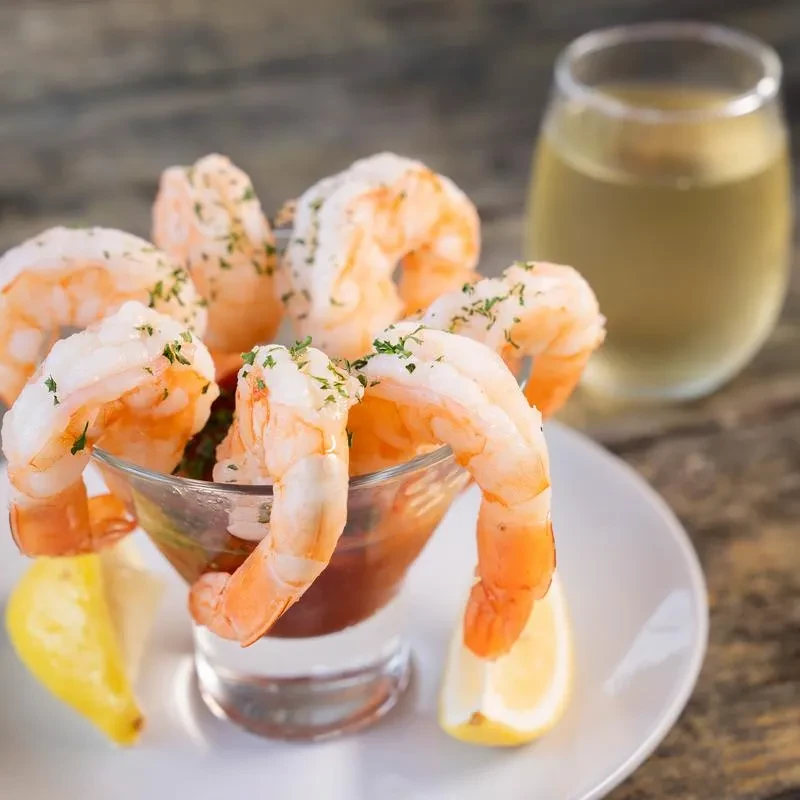 Shrimp cocktail in a glass, garnished with parsley and lemon wedges.