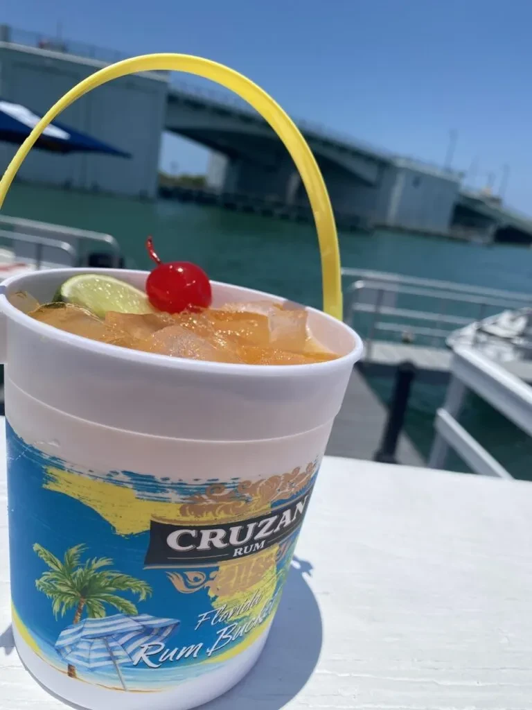 Florida Rum Bucket with cherry, lime by bridge over water.