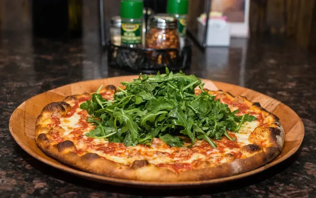 Golden-crusted pizza with melted cheese, tomato sauce, and fresh arugula.