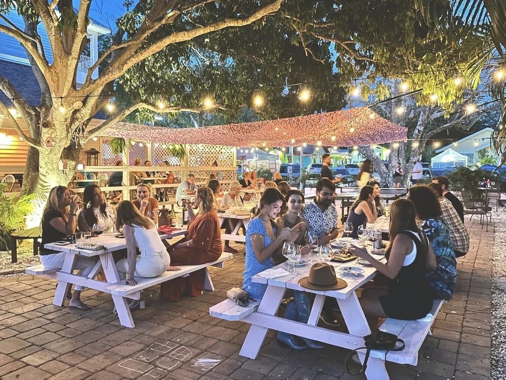 Patrons enjoying outdoor dining at dusk with string lights and hopscotch.
