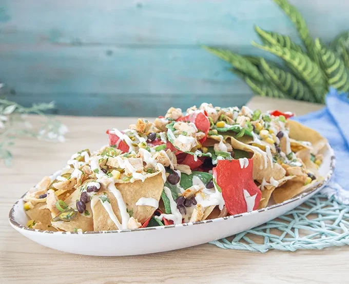 Large nachos platter with chicken, beans, corn, and creamy sauce.