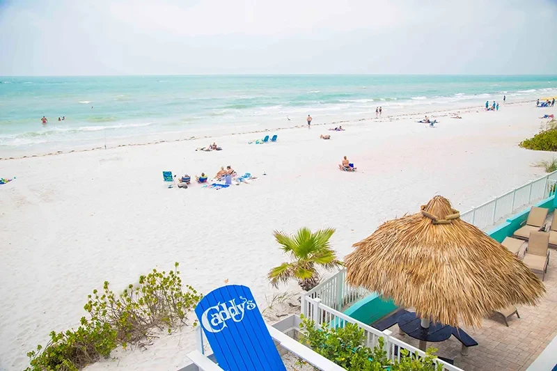 Elevated view of a bustling beach, turquoise ocean, with Caddy's patio.