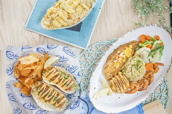 Overhead view of seafood platter, tacos, and pasta salad on a table.