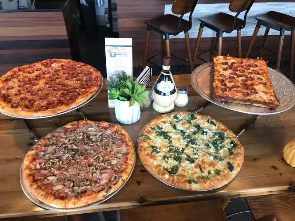 Four pizzas: pepperoni, ham/mushroom, spinach/feta, on a restaurant table.