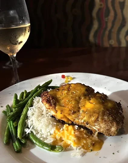 Breaded chicken with yellow sauce, rice, green beans, and white wine.