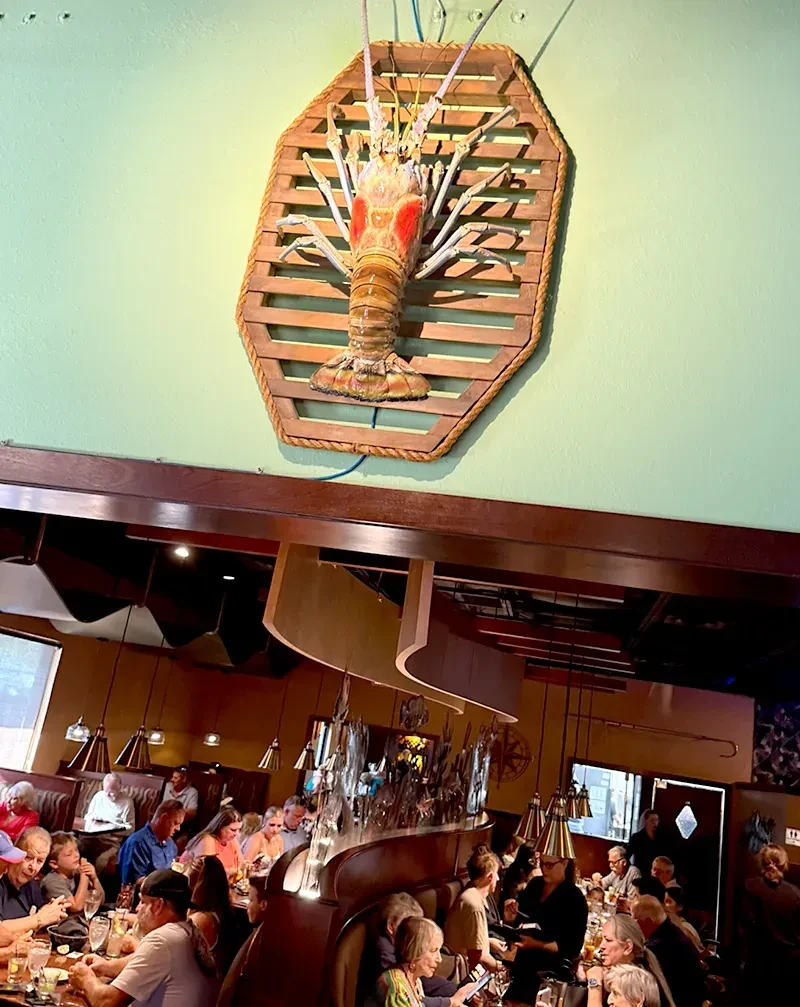 Bustling restaurant with a prominent lobster sculpture on a mint wall.