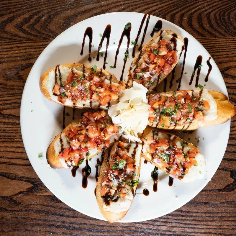 Overhead view of bruschetta with cheese, tomatoes, and balsamic glaze.