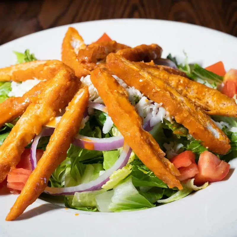 Salad with breaded chicken, lettuce, tomatoes, cheese, and onion.
