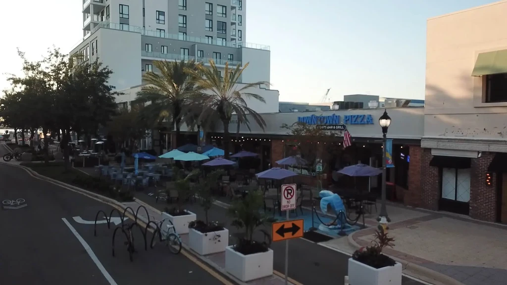Downtown Pizza Sports Bar & Grill with colorful umbrellas and palm trees.