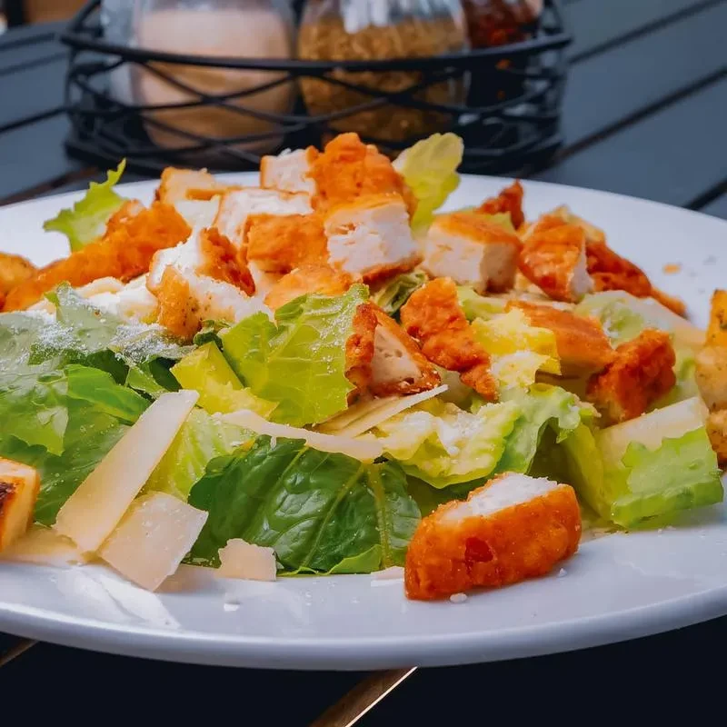 Caesar salad with fried chicken, crisp lettuce, and Parmesan cheese.