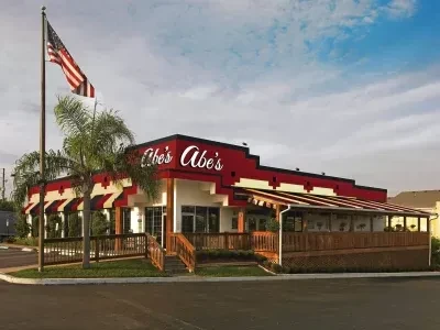 Exterior of Abe's red and white restaurant with patio and American flag.