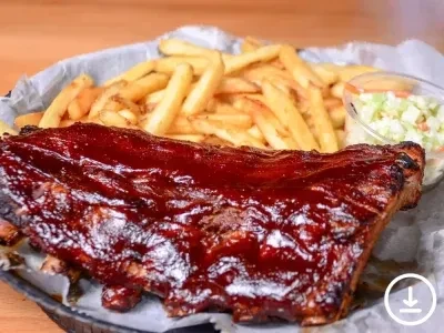 Close-up of barbecued ribs, french fries, and coleslaw in a basket.