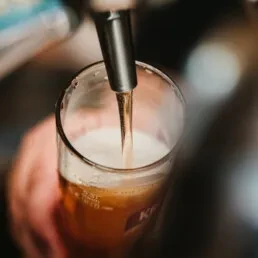 Close-up of beer pouring from a tap into a glass.