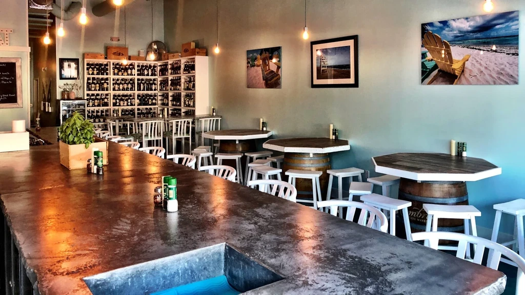 Wine bar interior: rustic decor, wine shelves, and barrel tables.