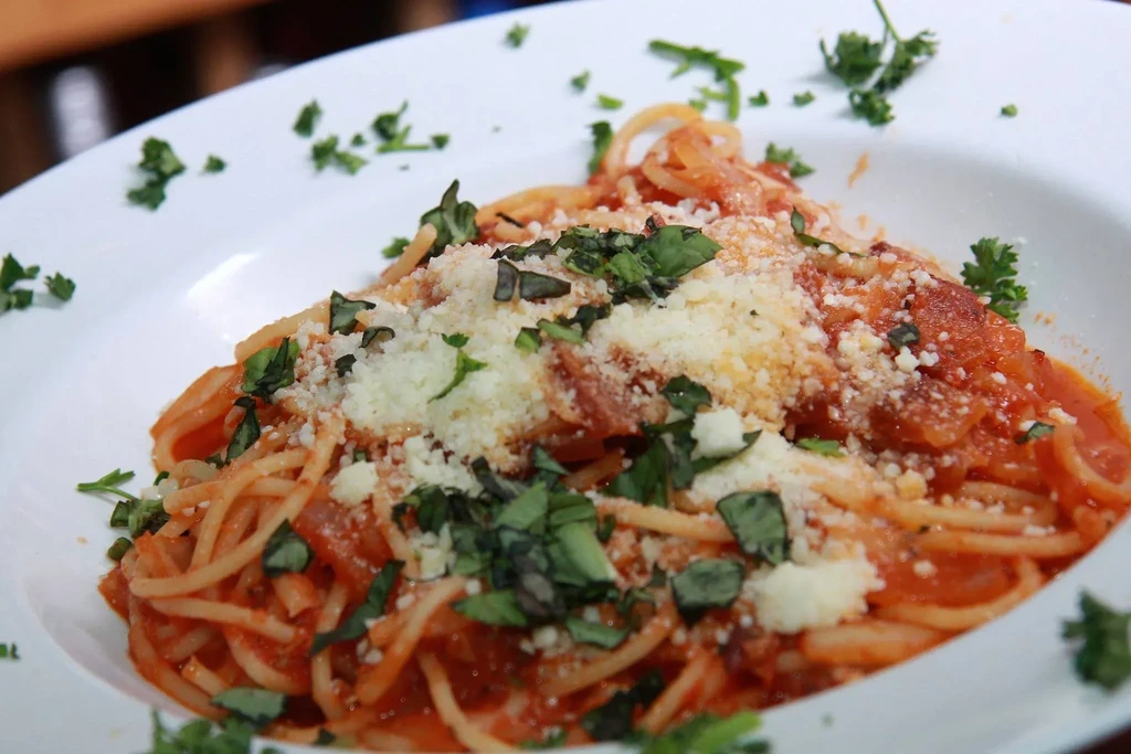 Spaghetti with tomato sauce, grated cheese, and fresh herbs.