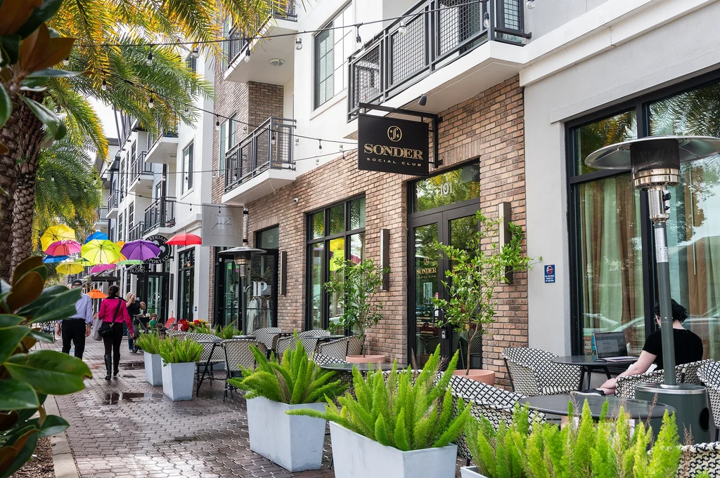 Sonder Social Club exterior, lively street, outdoor seating, colorful umbrella canopy.