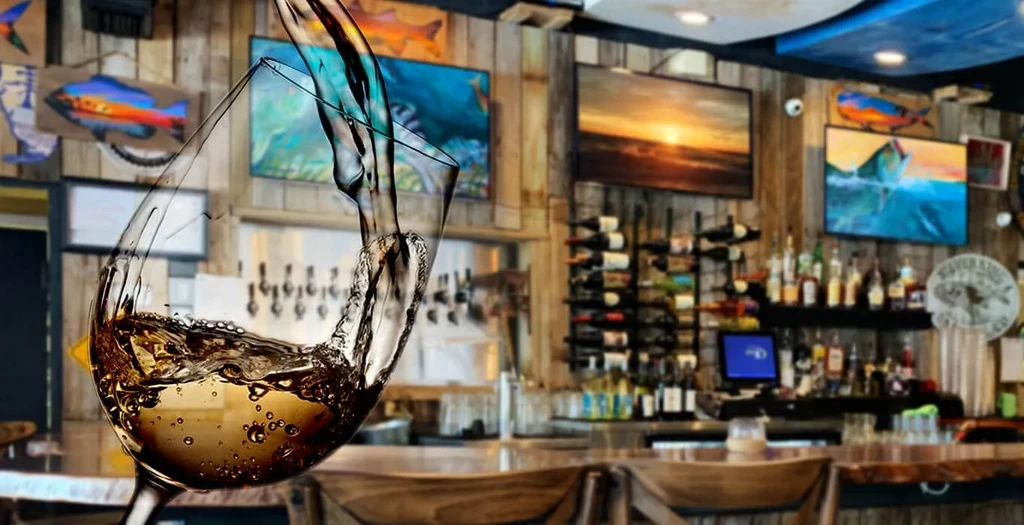 White wine splashes into a glass in a rustic bar.