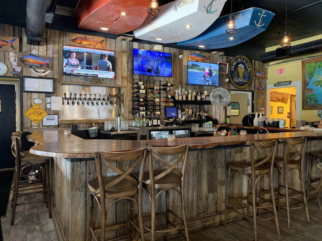 Rustic nautical bar with wooden counter, beer taps, and boat hulls.