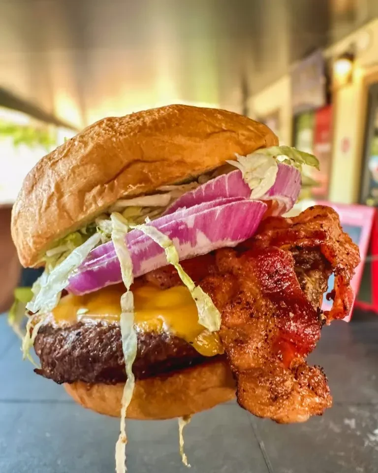 Close-up burger with beef, melted cheese, crispy bacon, lettuce, onion.