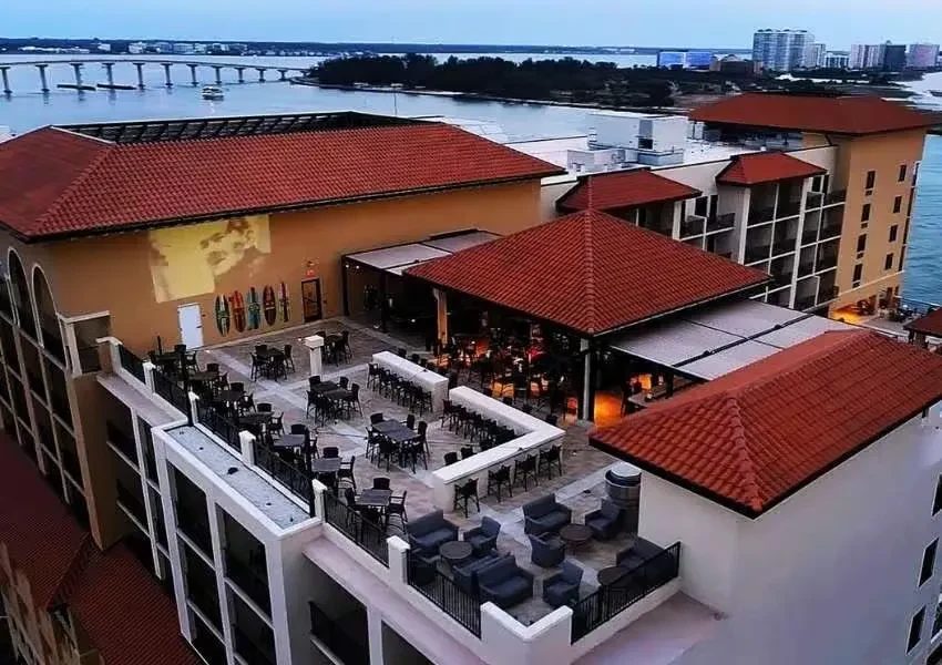 Elevated view of a resort's terraced outdoor restaurants overlooking a bay at dusk.