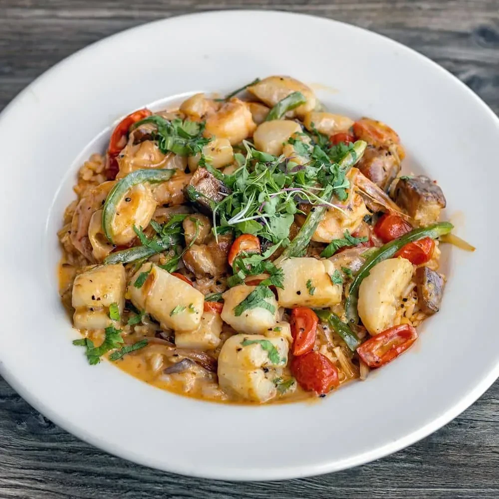 Overhead: creamy seafood with scallops, shrimp, vegetables, rice, and herbs.