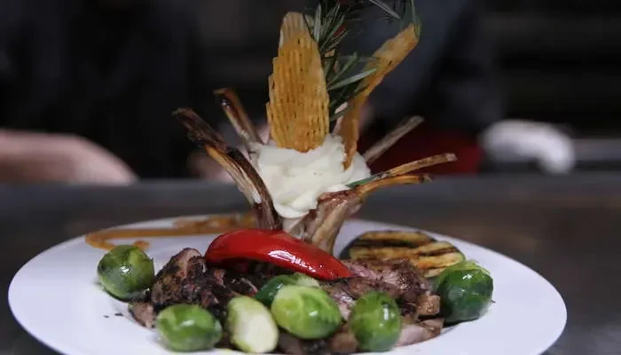 Rack of lamb with exposed bones, mashed potatoes, and grilled vegetables.