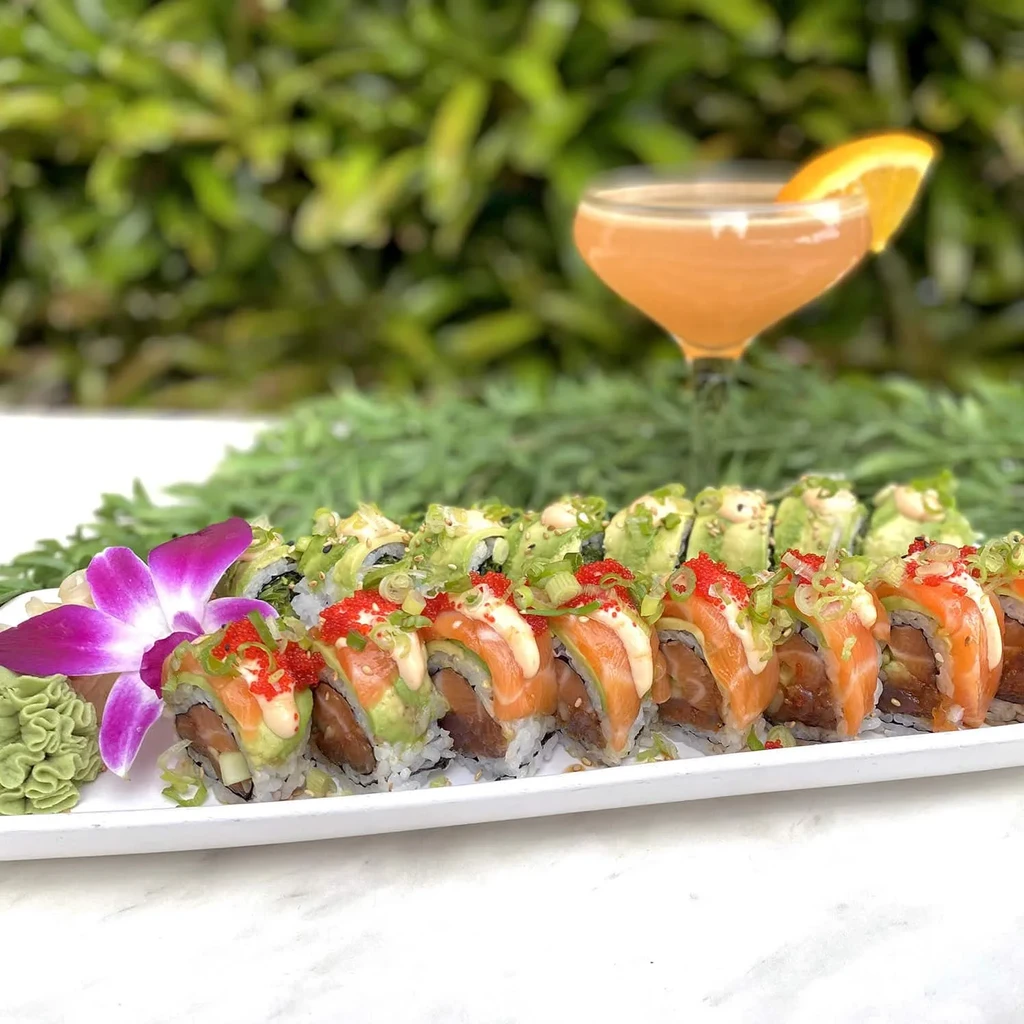 Platter of salmon and avocado sushi rolls with orchid and wasabi.