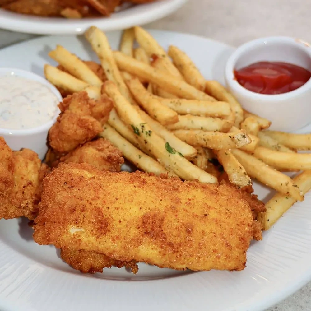 Fried fish or chicken tenders, seasoned fries, ketchup, and white sauce.
