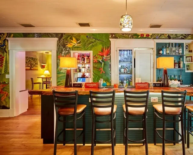 Restaurant bar with a wooden counter, bar stools, and tropical mural.
