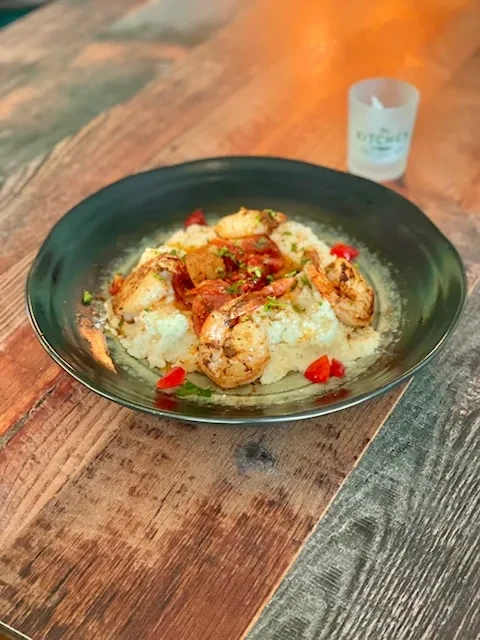 Close-up of shrimp and grits garnished with red vegetables and herbs.