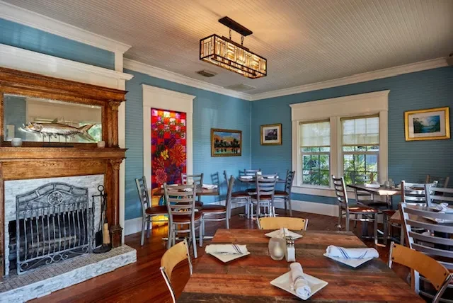 Restaurant dining room with blue striped walls, fireplace, and stained glass art.