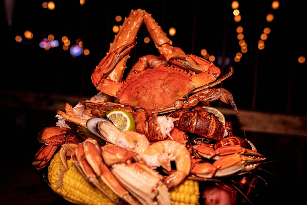 Seafood boil platter with red crab, shrimp, mussels, lobster, and corn.