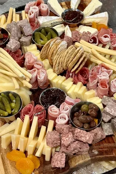 Artfully arranged charcuterie and cheese board with meats, cheeses, and fruits.