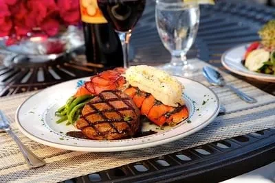 Plated grilled steak, lobster tail, mashed potatoes, and asparagus.