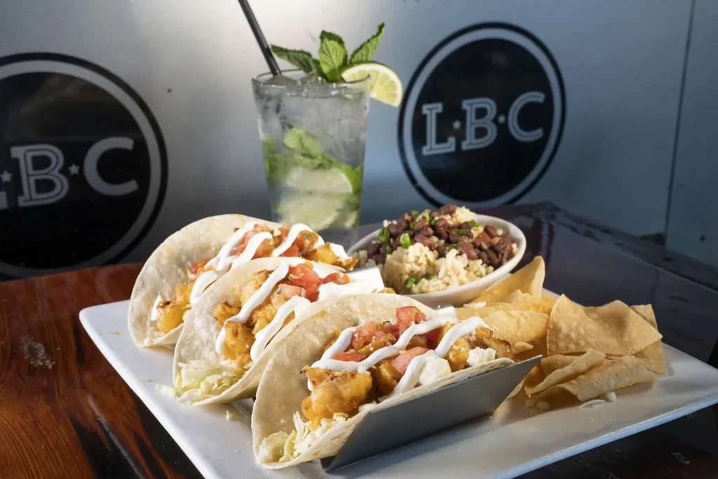 Three fried tacos, tortilla chips, rice, black beans, and a cocktail.
