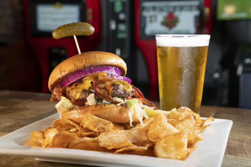 Gourmet burger with melted cheese, crispy chips, and a cold beer.