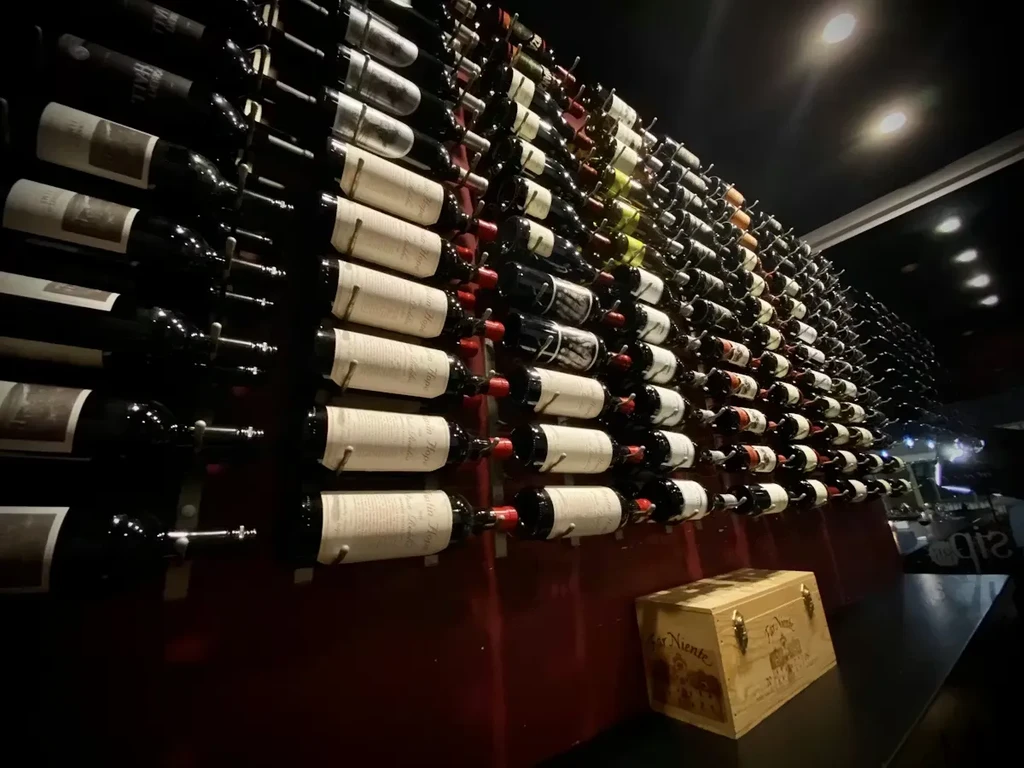 Large, dimly lit wine rack holding numerous bottles and a wooden crate.