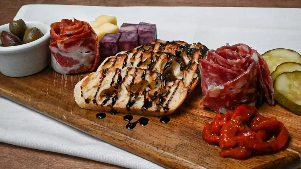 Artfully arranged charcuterie board with meats, cheeses, olives, and balsamic bread.