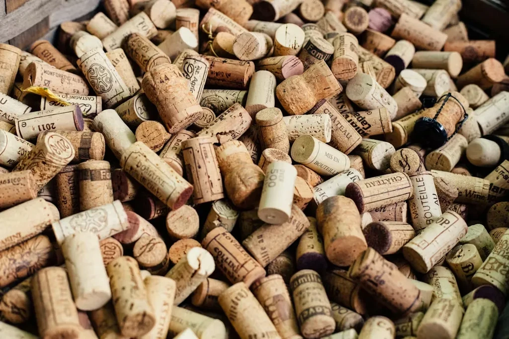 Large pile of used wine and champagne corks, some with labels.