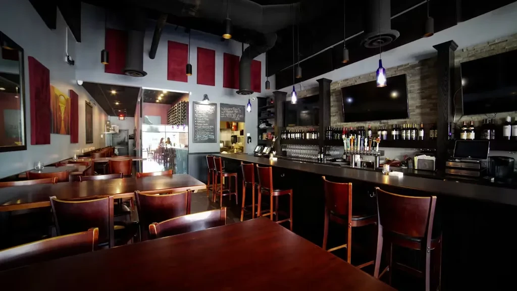 Modern restaurant interior with a dining area and well-stocked bar.