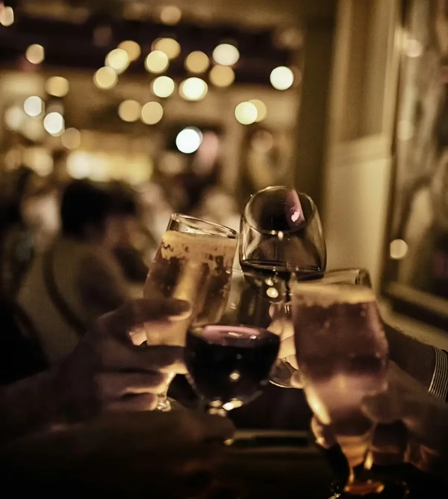 Four hands clinking glasses of beer and wine in a toast.