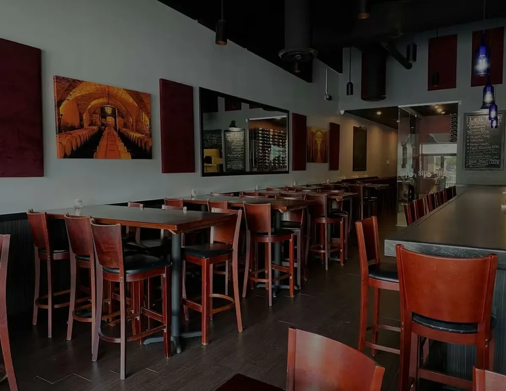 Empty modern bar interior with high-top tables and industrial lighting.